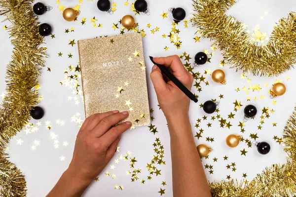Golden notebook with shiny glitter cover, golden and black Christmas balls, baubles, garland and confetti stars — Stock Photo, Image