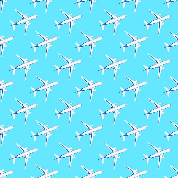 青い背景に白い飛行機とシームレスなパターン。紙、布や壁紙のための繰り返し旅行プリント。上からおもちゃの飛行機。旅行と利点の概念フラットレイアウト — ストック写真