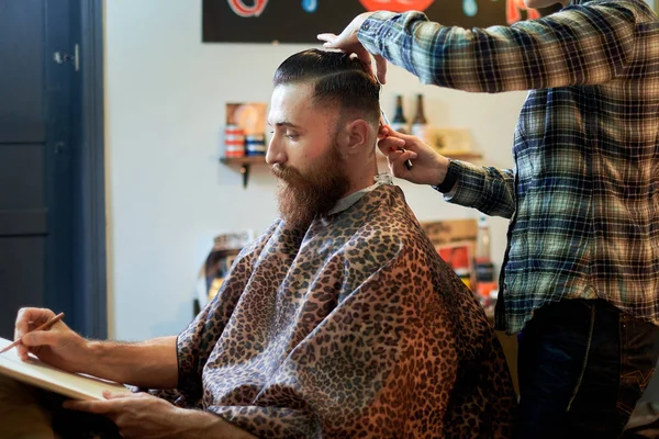 Mestre corta cabelo e barba de homens na barbearia — Fotografia de Stock