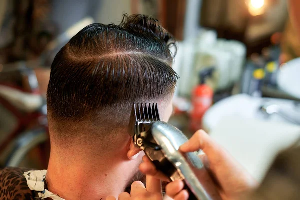 Mestre corta cabelo e barba de homens na barbearia — Fotografia de Stock