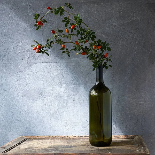Flesje etherische olie van rose heupen op houten achtergrond — Stockfoto