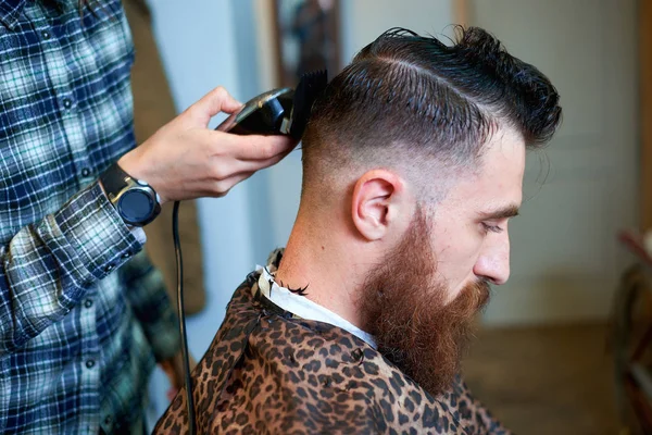 Master cuts hair and beard of men in the barbershop