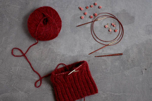 Rode onvoltooide trui met een bal van draden op een grijze achtergrond — Stockfoto