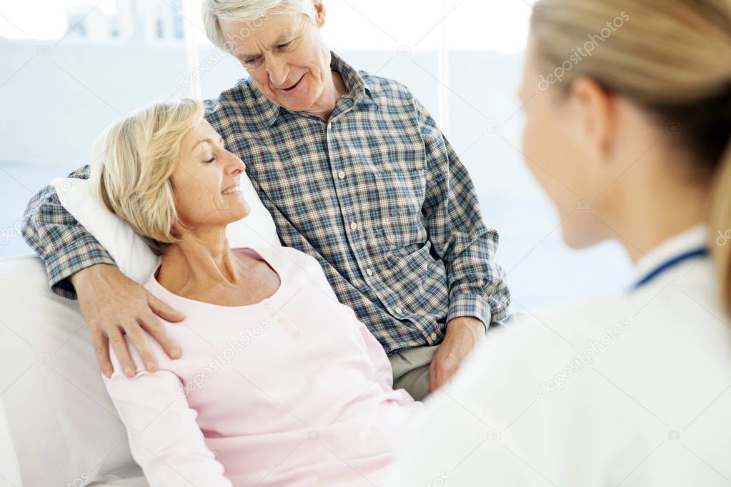 Loving senior couple together at the hospital with doctor - Arm around shoulder