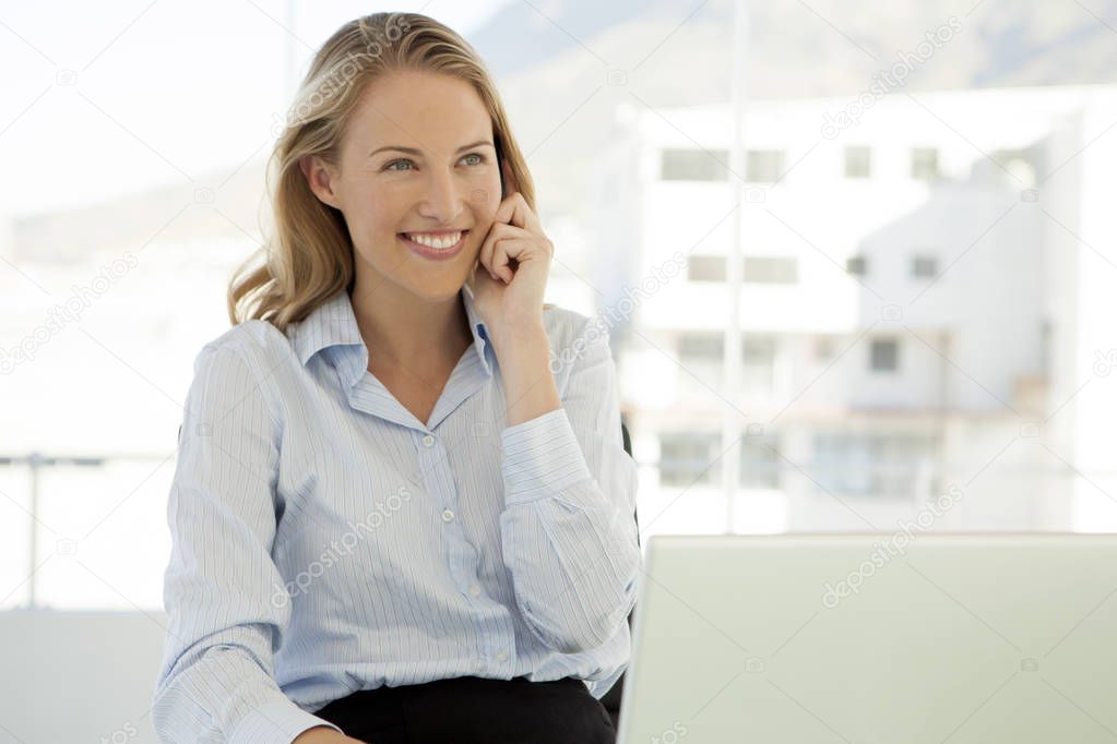 Woman on the phone at workplace - young beautiful businesswoman using smartphone for a call in office - portrait