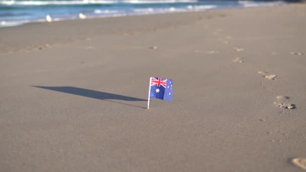 Australische vlag op het zand oceaan strand zwaaiend in de wind. — Stockvideo