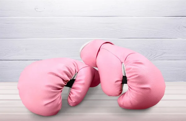 Pink boxing gloves on wooden table