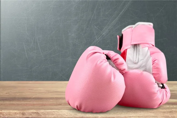 Pink boxing gloves on wooden table