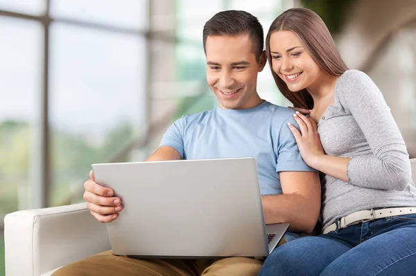 Casal sorrindo com laptop no sofá — Fotografia de Stock