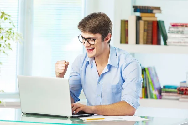 Homem feliz trabalhando no laptop na biblioteca — Fotografia de Stock