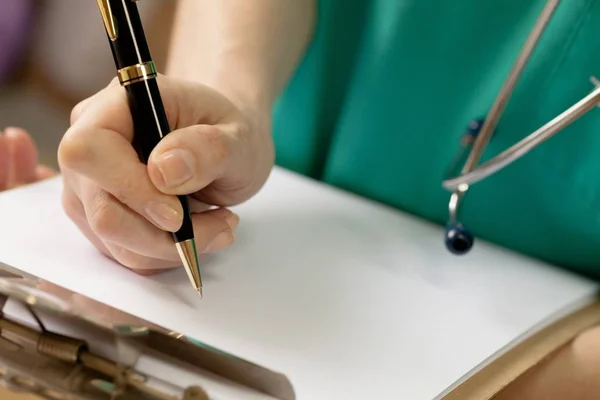 Doctor escribiendo en un portapapeles — Foto de Stock