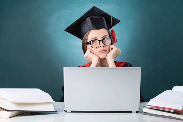 Megunta / gondolkodó női diplomás az osztályteremben, használ egy Laptop — Stock Fotó