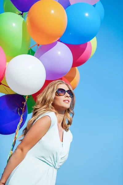 Junge Frau hält ein Bündel Luftballons in der Hand — Stockfoto