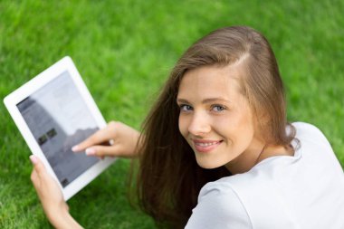 Bir Tablet bir parkta kullanan bir genç kadın portresi