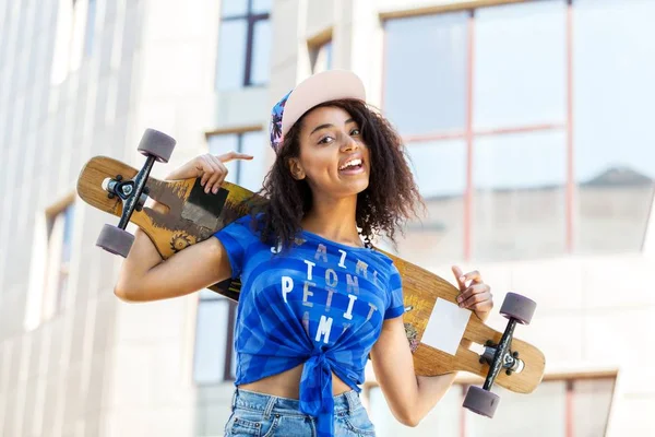 Jovem mulher segurando skate na cidade — Fotografia de Stock