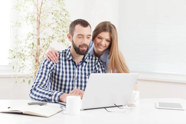 Jovem casal alegre trabalhando no laptop . — Fotografia de Stock