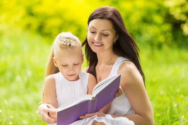 Anya olvasó egy könyv, a lánya a parkban — Stock Fotó