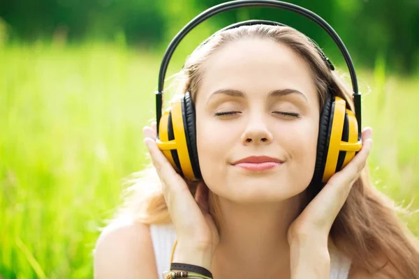 Hermosa mujer joven con auriculares al aire libre. Disfrutando de la música — Foto de Stock