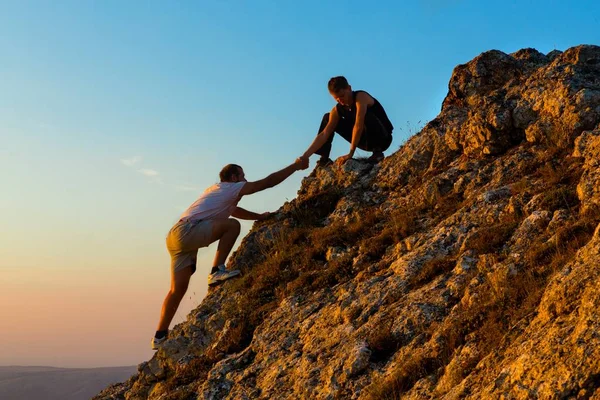 Mann klettert mit Hilfe eines anderen Mannes — Stockfoto