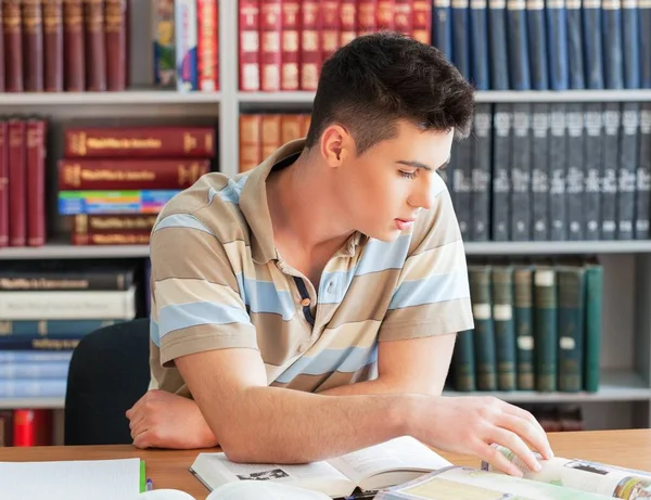 Retrato de jovens livros de leitura do sexo masculino com estantes com muitos livros em segundo plano — Fotografia de Stock