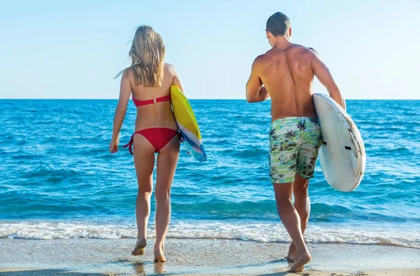 Groep vrienden met surfplanken loopt naar de Oceaan bij zonsondergang — Stockfoto