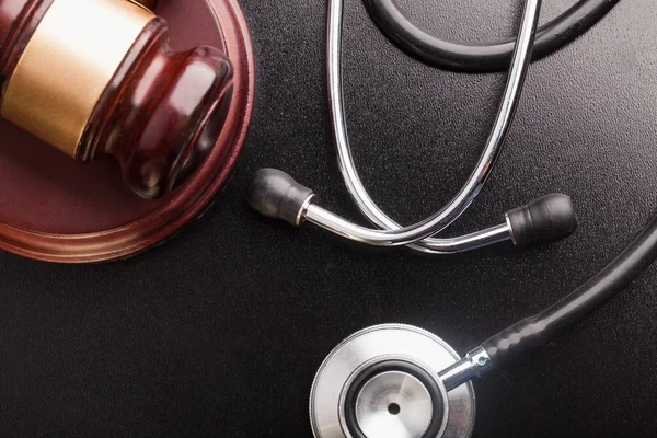 Wooden gavel and stethoscope on background