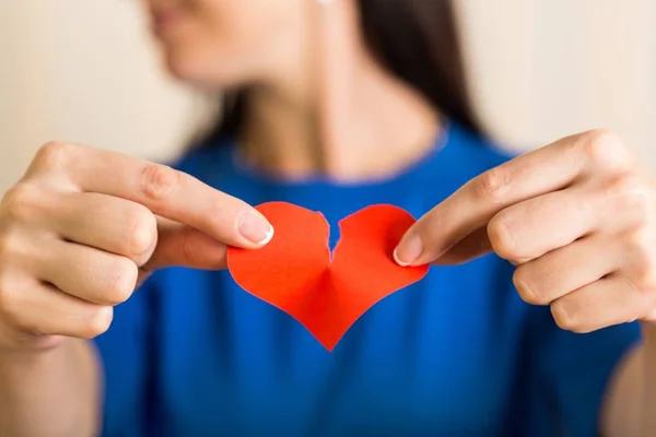 Manos femeninas sosteniendo un corazón roto — Foto de Stock