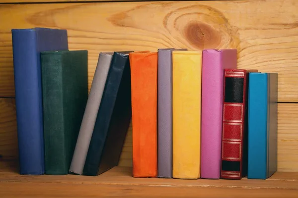 Βιβλία των διαφορετικών χρωμάτων σε ένα ξύλινο ράφι — Φωτογραφία Αρχείου