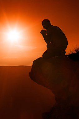 Kayanın üzerinde oturan adam dua