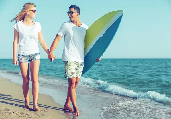 Hispanic couple walk on beach together with surfboard having fun outdoors — Stock Photo, Image