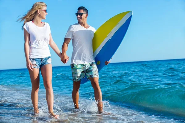 Hispanic couple walk on beach together with surfboard having fun outdoors — Stock Photo, Image