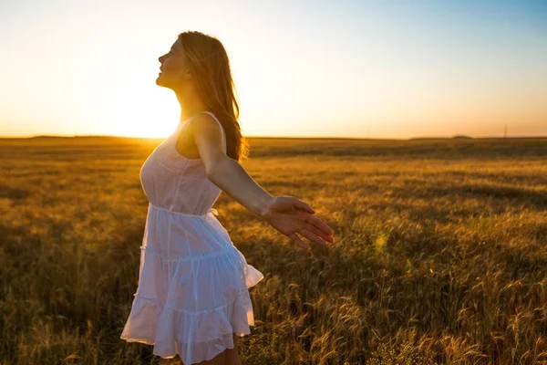 Joven mujer de pie en medio de un campo durante la puesta del sol —  Fotos de Stock