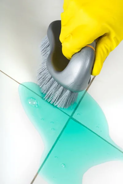 Hand in Gummihandschuh mit Bürste und Fliesen reinigen — Stockfoto