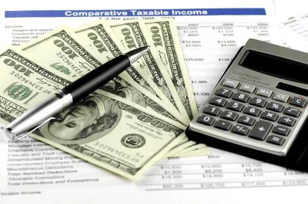 Notas de cem dólares com uma caneta, calculadora e planilha fiscal — Fotografia de Stock