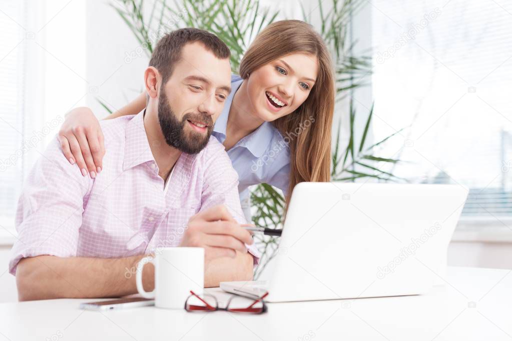 Cheerful young couple working on laptop.