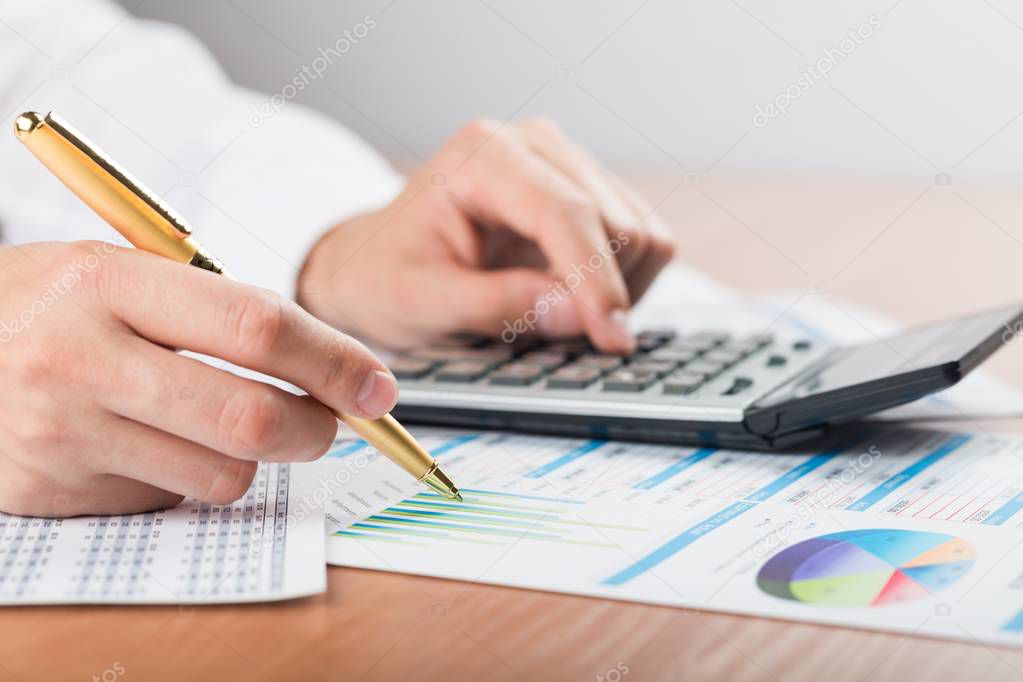Close-up of a Businessman Analyzing Business Graphs with Calculator