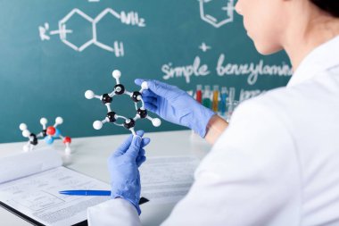Bir moleküler yapısı ile kara tahta arka plan üzerinde tutan kadın bilim adamı