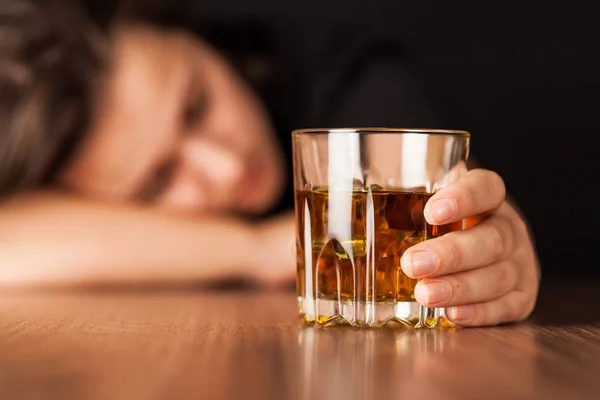 Mulher bêbada dormindo no balcão de bar segurando um copo de uísque — Fotografia de Stock