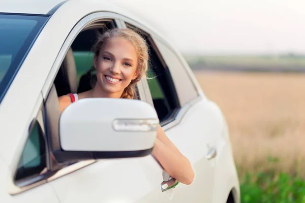 Retrato de una joven sonriente mirando por la ventana de su coche — Foto de Stock
