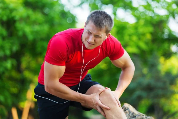 Uszkodzenia mięśni. człowiek z zwichnięcie mięśni ud. zawodnik w spodenki sportowe ściskając jego mięśnie ud po ciągnięcie lub wysiłku ich podczas joggingu na plaży — Zdjęcie stockowe
