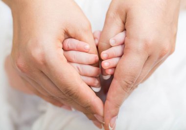 kadın parmağını tutan bebek.