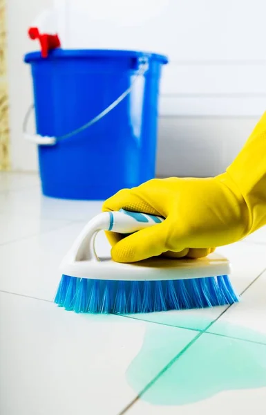 Main dans le gant en caoutchouc tenant une brosse et des carreaux de nettoyage dans la salle de bain — Photo