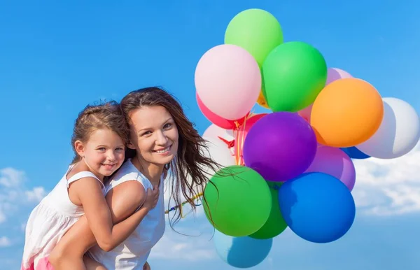 Mãe com filha segurando balões coloridos — Fotografia de Stock