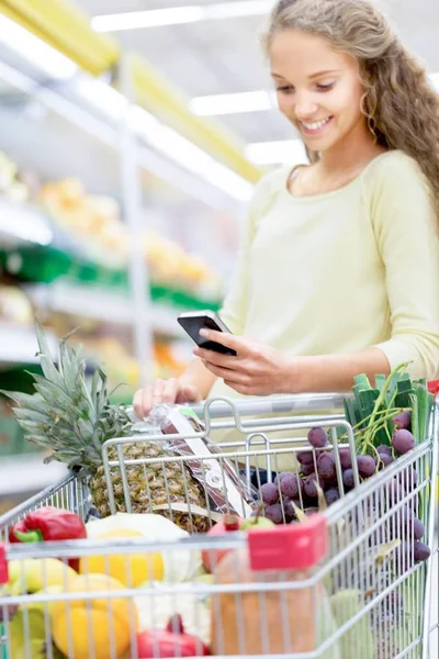 Portrét Mladé Šťastné Ženy Nákupním Košíkem Mobilním Telefonem Supermarketu — Stock fotografie