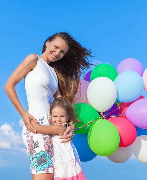 Mãe com filha segurando balões coloridos — Fotografia de Stock