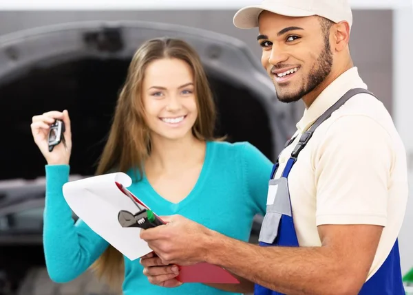 Een monteur en een Smiling vrouw houdt haar autosleutels — Stockfoto