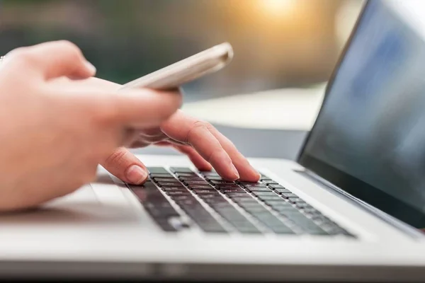 Manos Escribiendo Teclado Portátil Moderno Utilizando Teléfono Inteligente — Foto de Stock