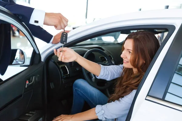 Auto verkoper verkoopt een auto aan gelukkige klant in de auto dealer en overhandigt de sleutels — Stockfoto