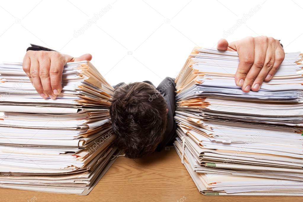 Tired businessman at office with pile of documents