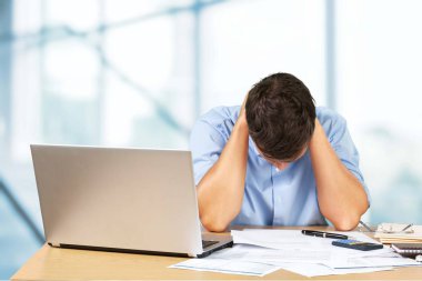 Office belgeleri ve dizüstü bilgisayar ile yorgun işadamı